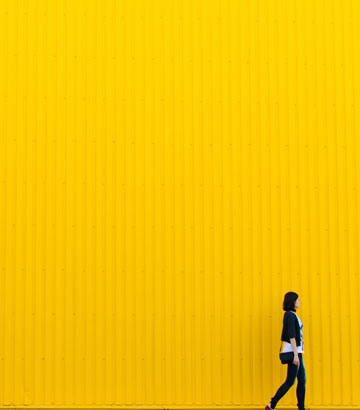 Eine Frau geht vor einer gelben Wand lang