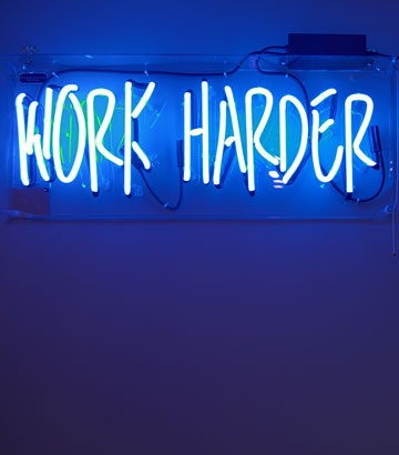 Der Begriff "work harder" in blauer Leuchtschrift